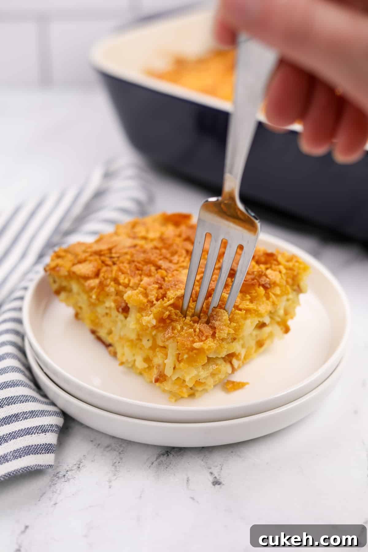 A fork taking a small portion of breakfast casserole from a plate.
