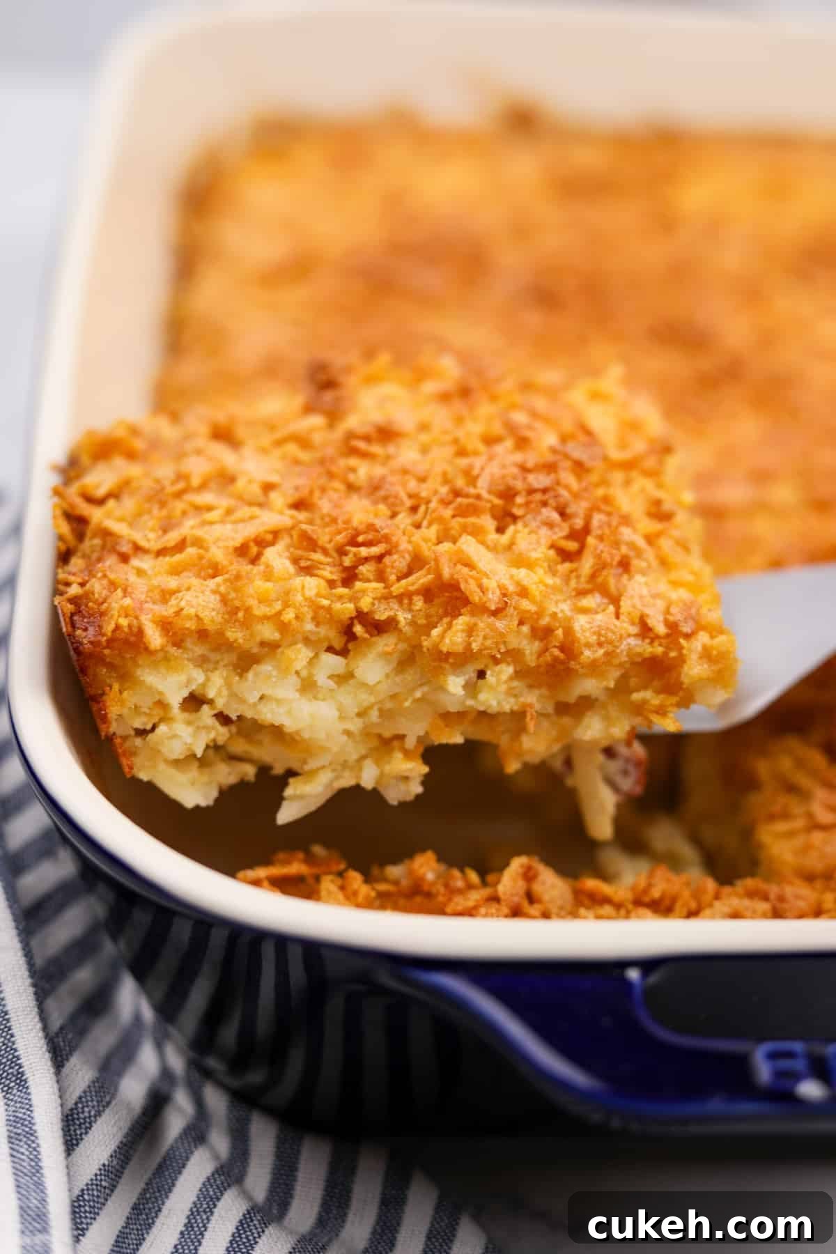 Lifting a portion of hash brown casserole from a baking dish.