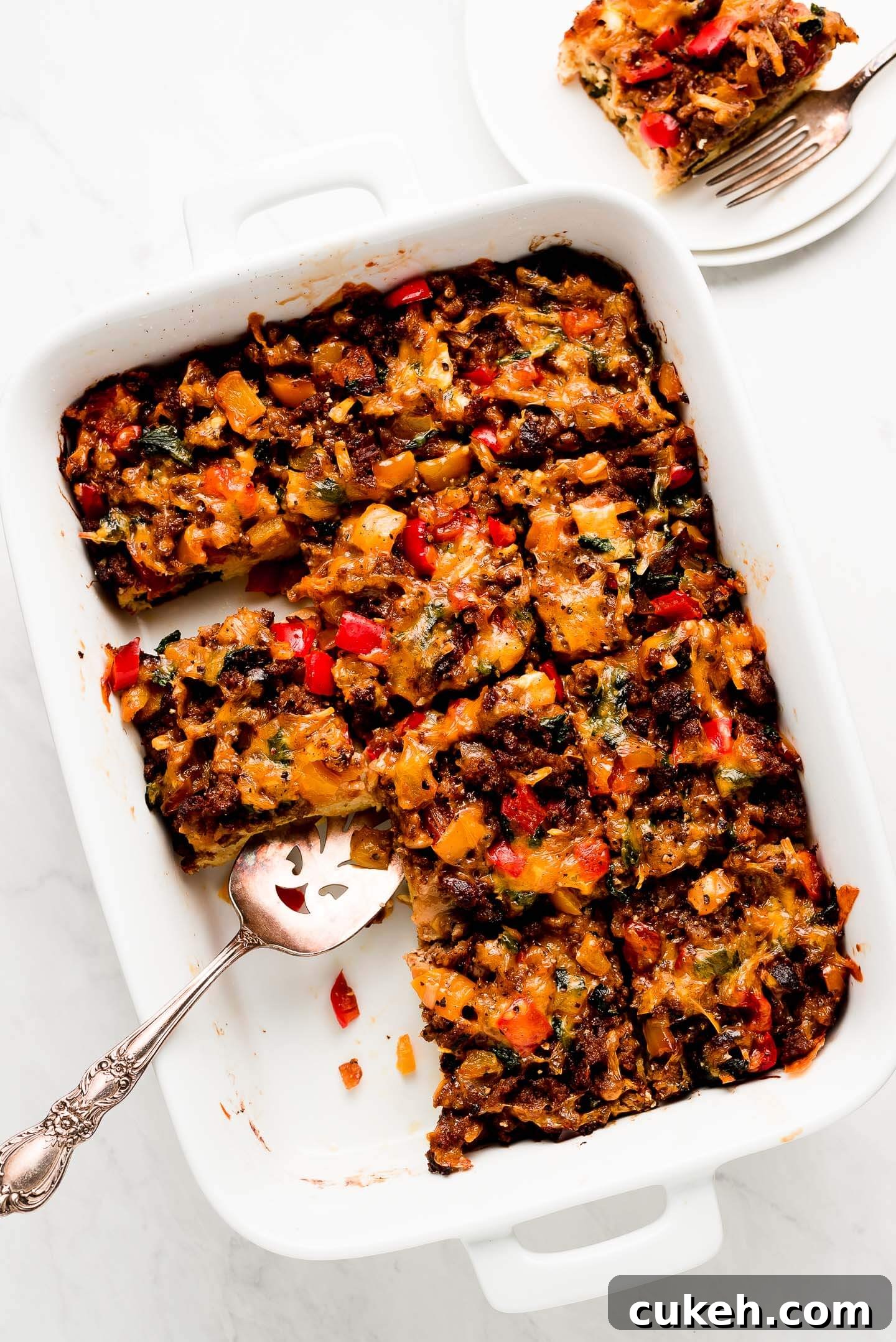 White dish of squares of egg and sausage breakfast casserole.