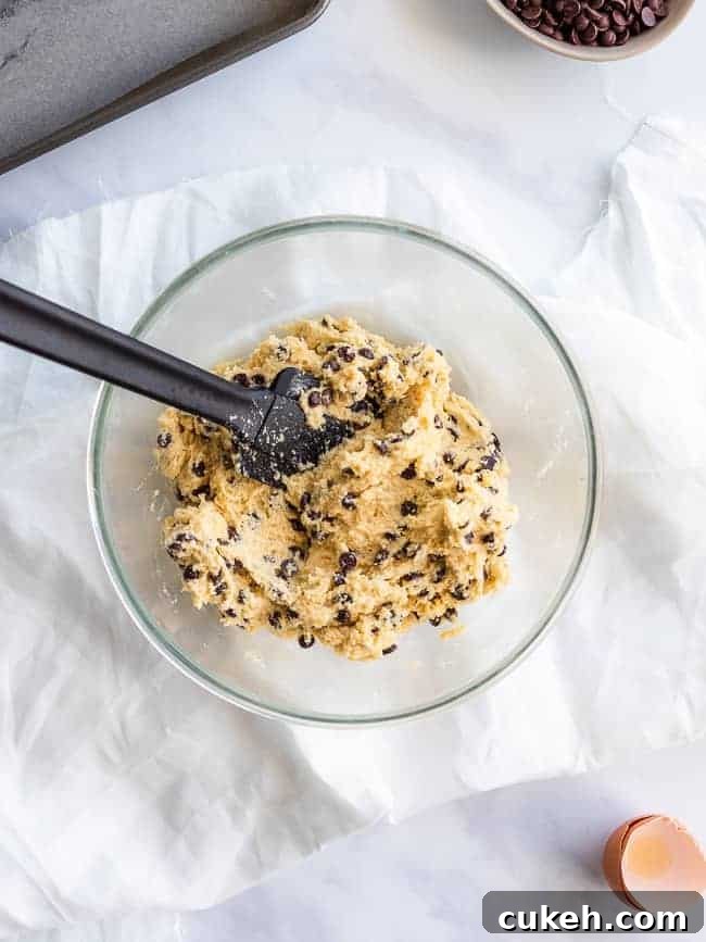 glass mixing bowl on white table cloth filled with cookie dough