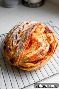Side angle of pepperoni pizza sourdough bread on cooling rack with designs on the top of the loaf.