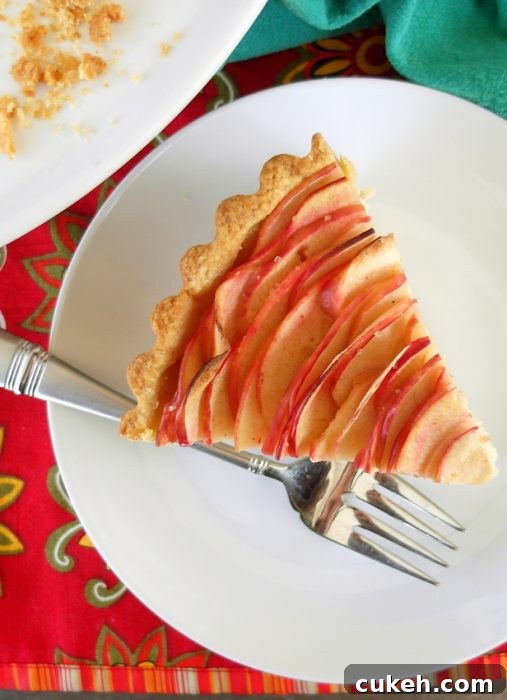 A slice of chai apple cheesecake tart with a fork on a white plate.