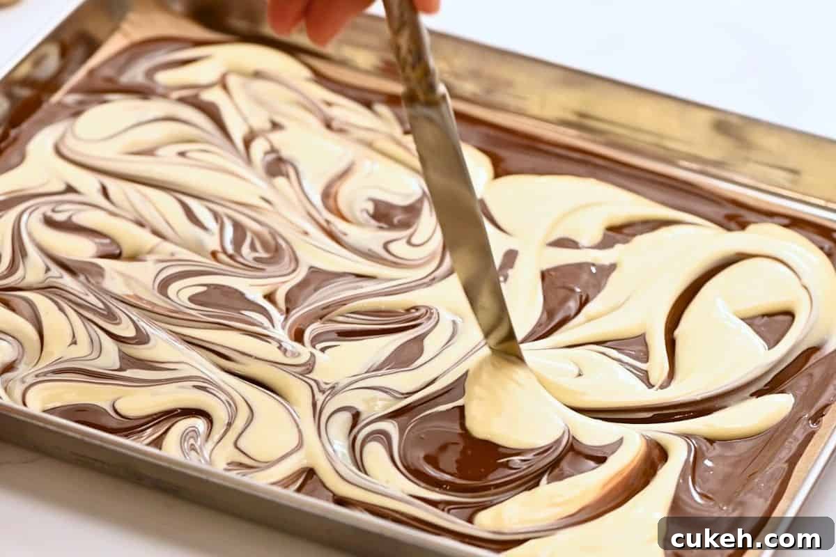 Butter knife swirling melted white chocolate into melted dark chocolate.