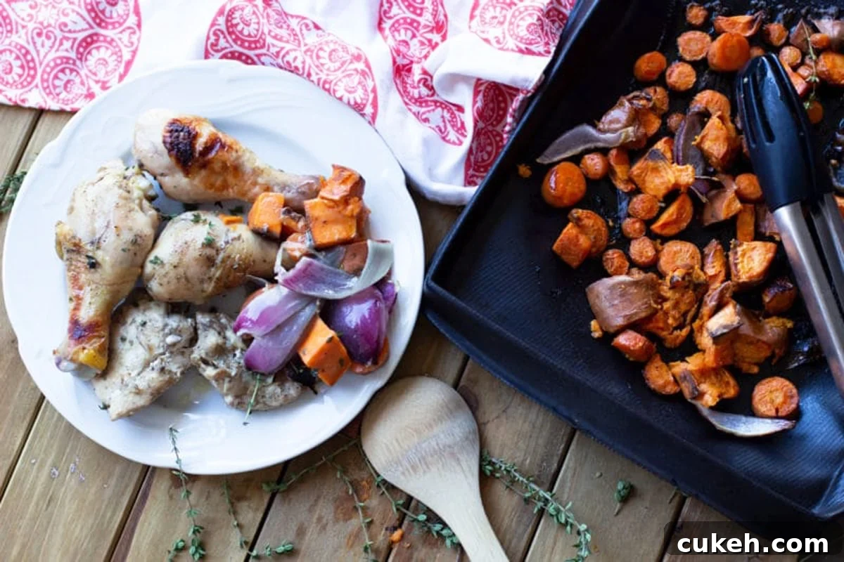 White plate with oven baked chicken, side of carrots, sweet potatoes, and red onions.