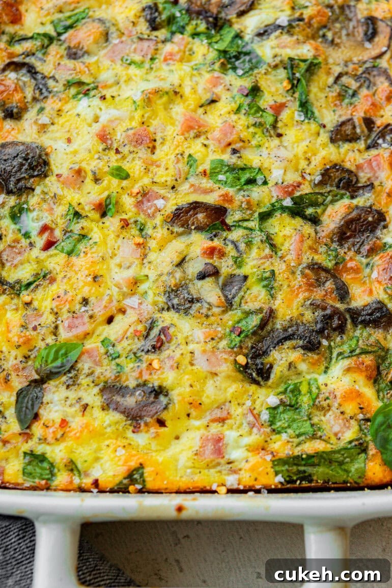 a baked egg casserole with sauteed mushrooms, spinach, cheese, and diced ham