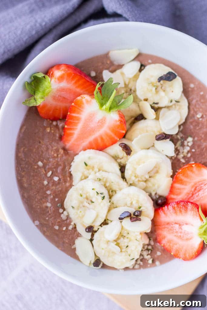 Chocolate oatmeal breakfast bowl served with fresh strawberries and banana