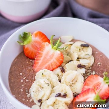 Healthy chocolate oatmeal porridge topped with banana and fresh strawberries