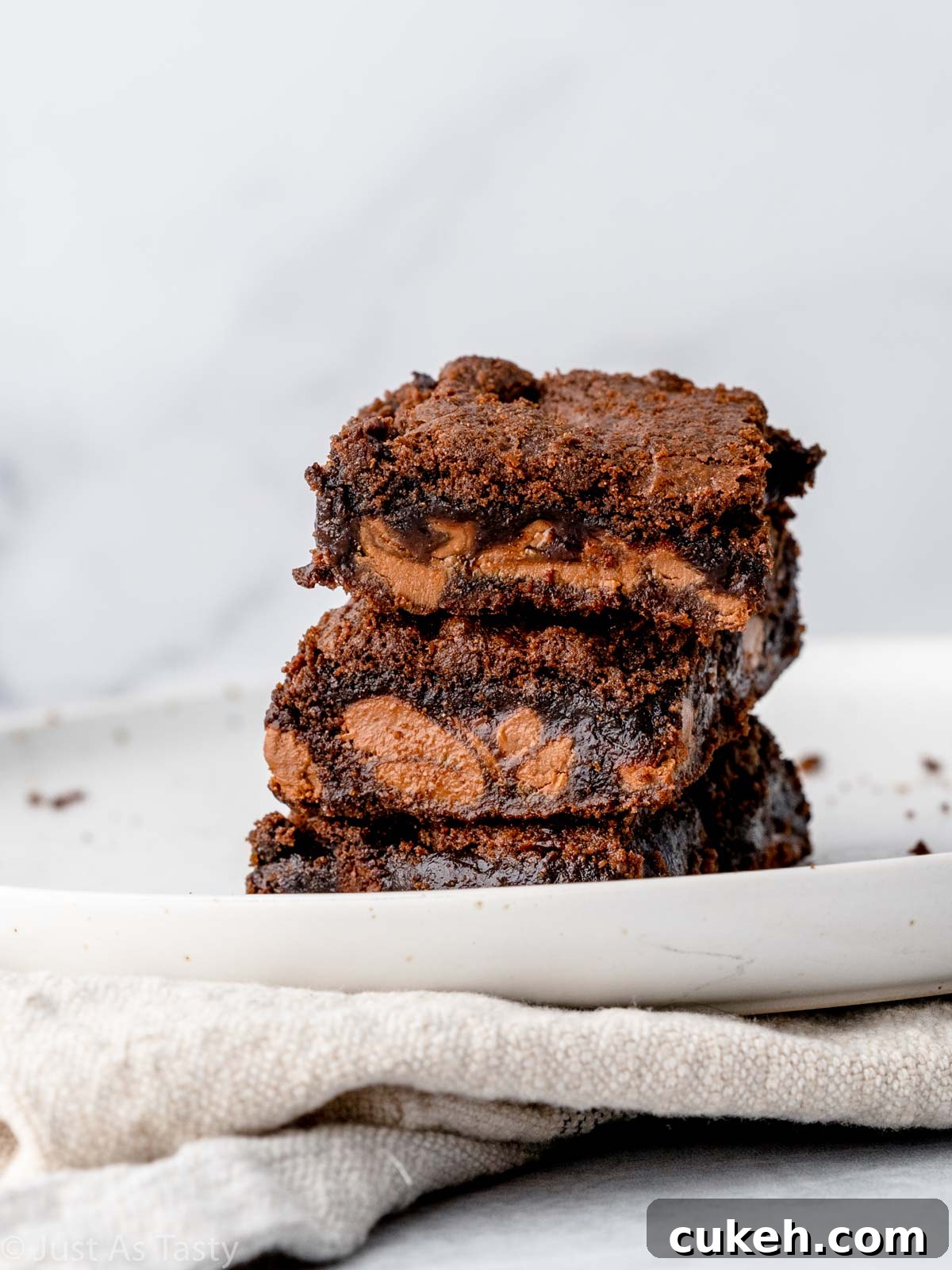 Stack of three Rolo brownies on a plate.