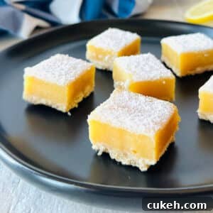 lemon bars with graham cracker crust on a black plate.