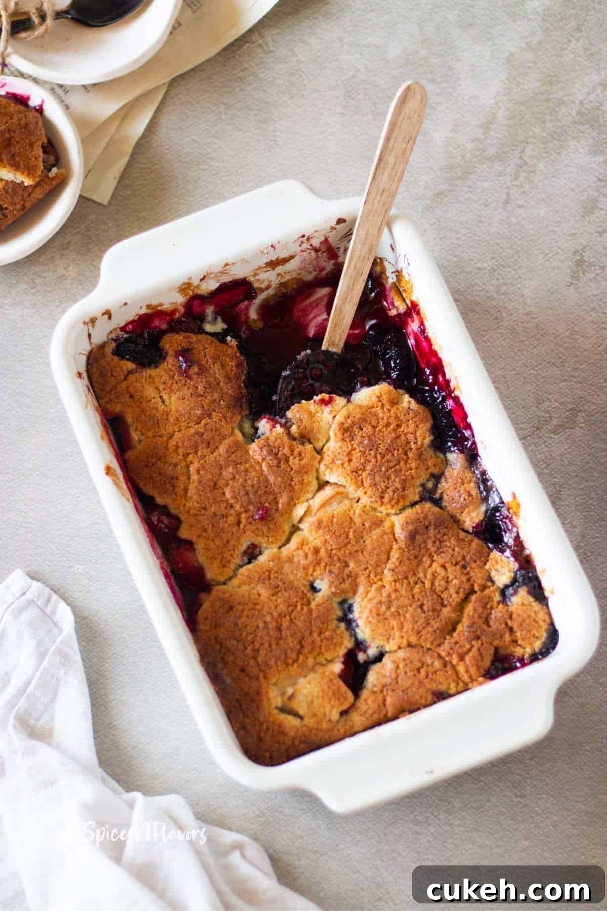 fruit cobbler from the baking dish with tea towel and bowls on side ready to be served
