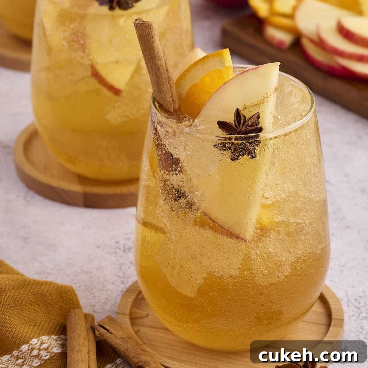 Glass of apple cider punch garnished with fresh apple slices and a cinnamon stick.