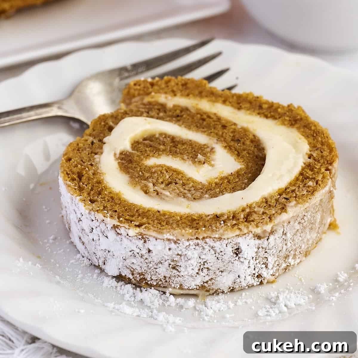 A slice of rolled pumpkin cake with cream cheese filling.