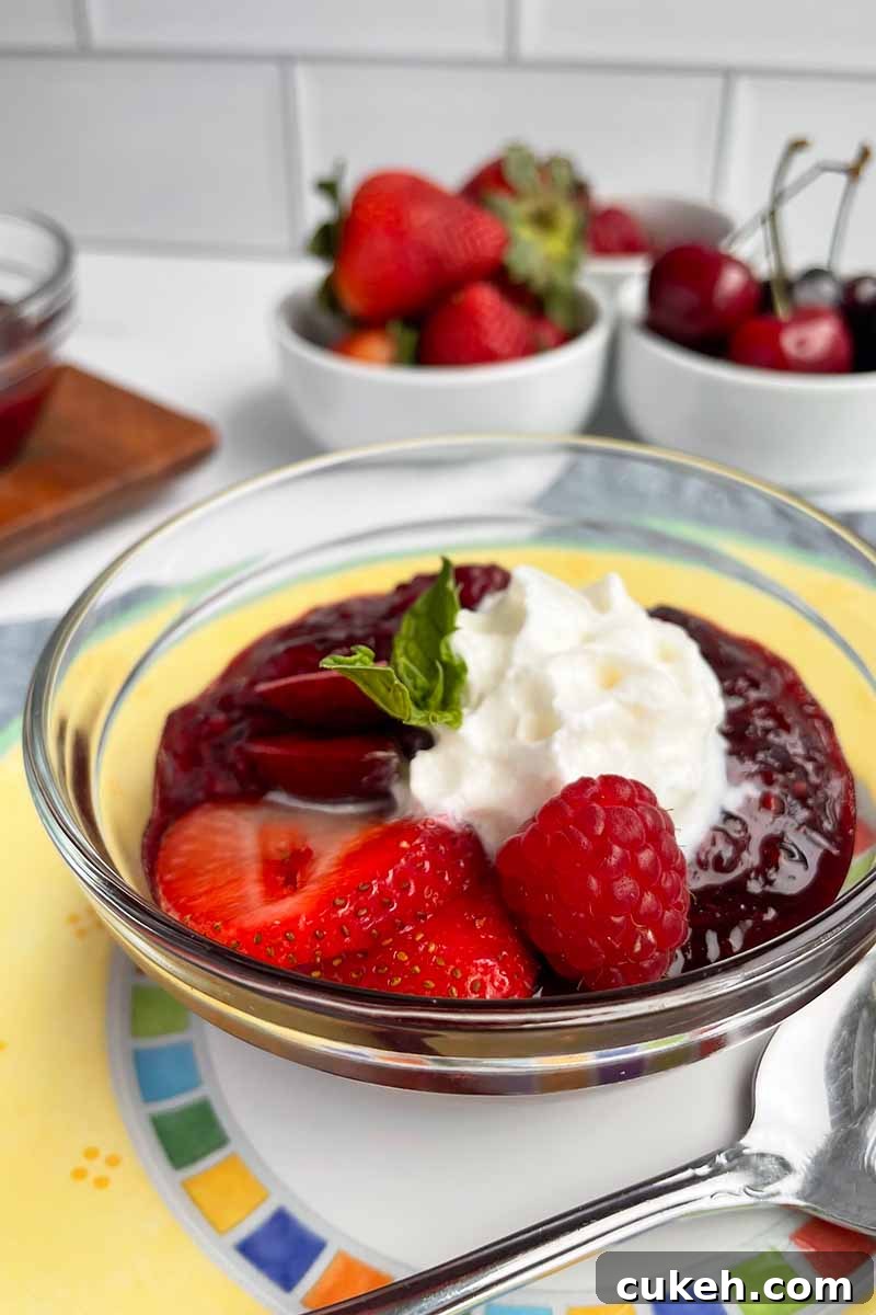 Vertical image of a metal spoon next to a maroon compote topped with whipped cream and mint on a yellow plate.