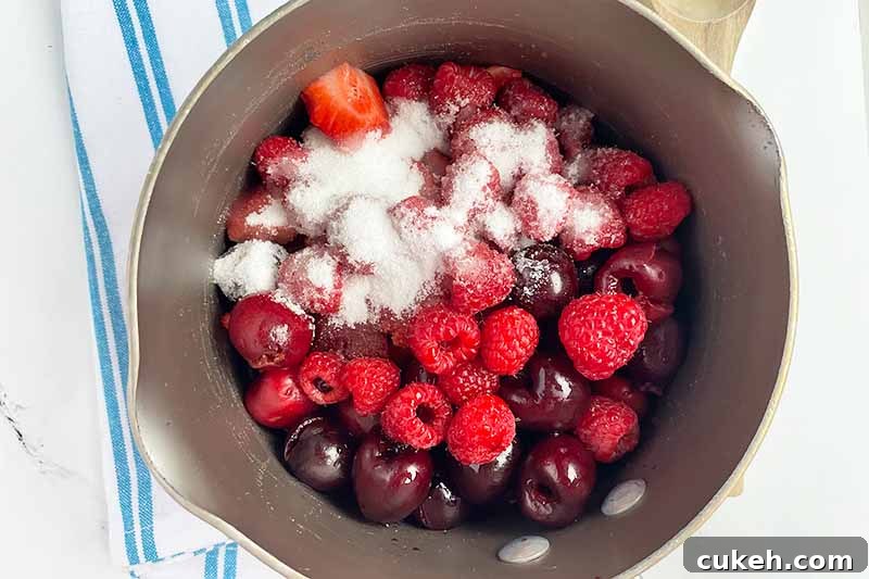 Horizontal image of cooking assorted fruit with sugar in a pot.