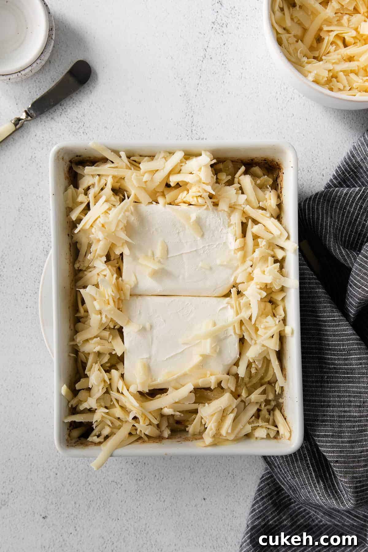 Cheeses ready for the dip Cream cheese and shredded cheese in a casserole dish for french onion dip.