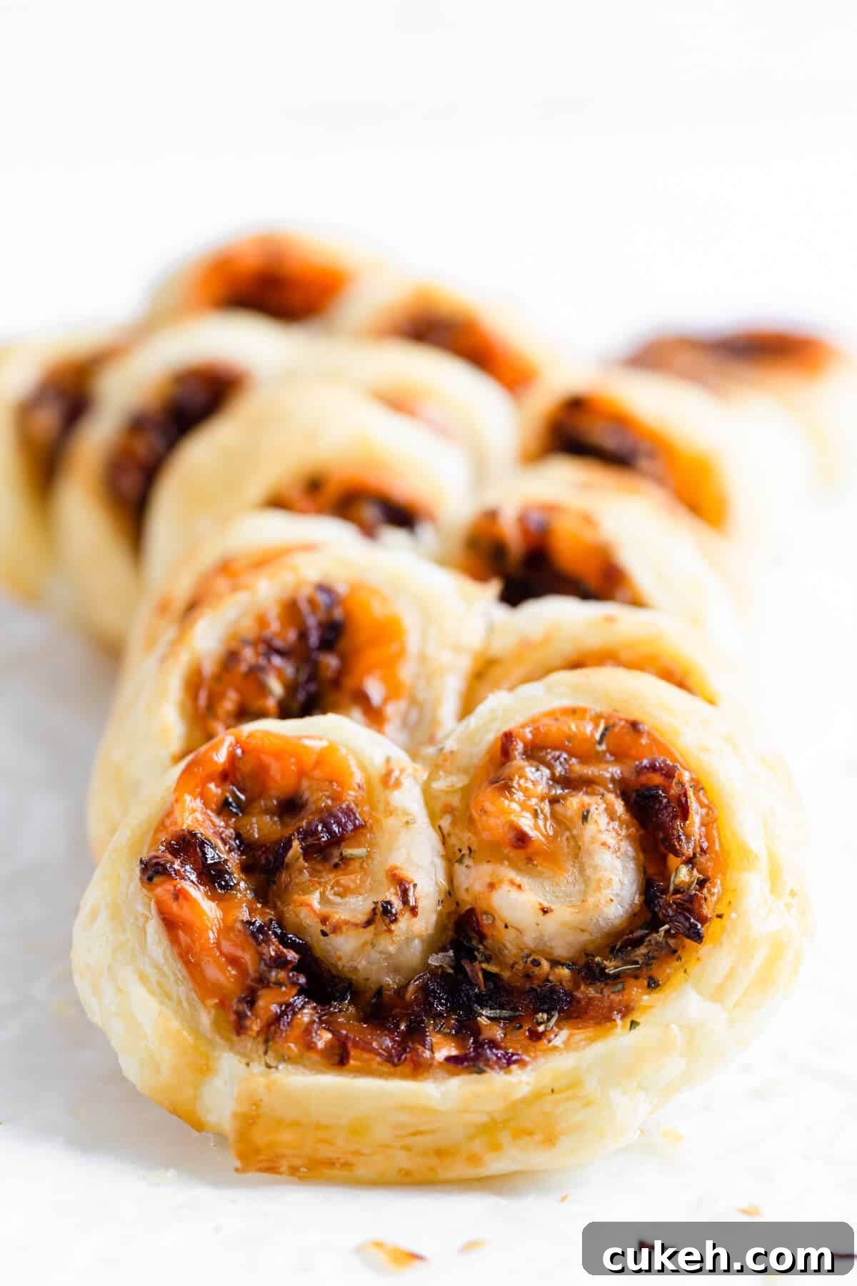 super close up of cream cheese and caramelised onion palmiers on white surface