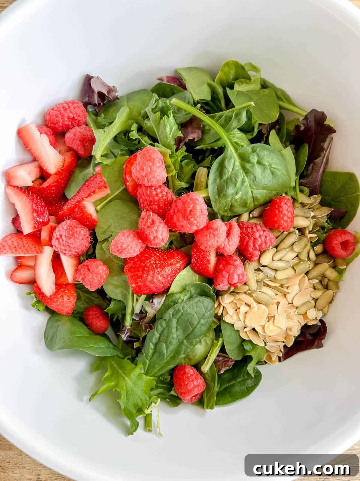 Salad with berries, almonds and pumpkin seeds on top.