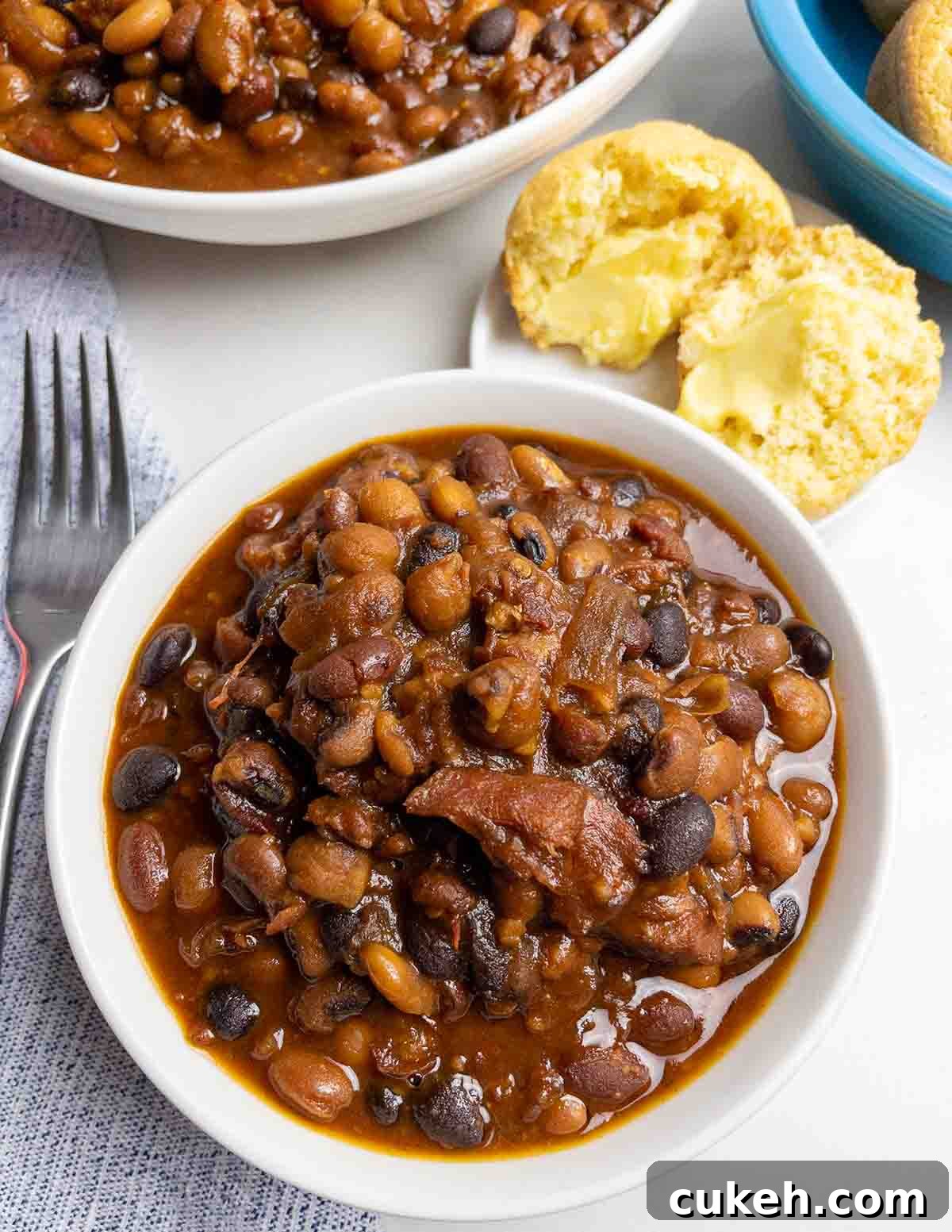 64 Tasty Leftover Ham Recipes for Every Meal 15 Top down view of a bowl of baked beans containing pieces of ham.