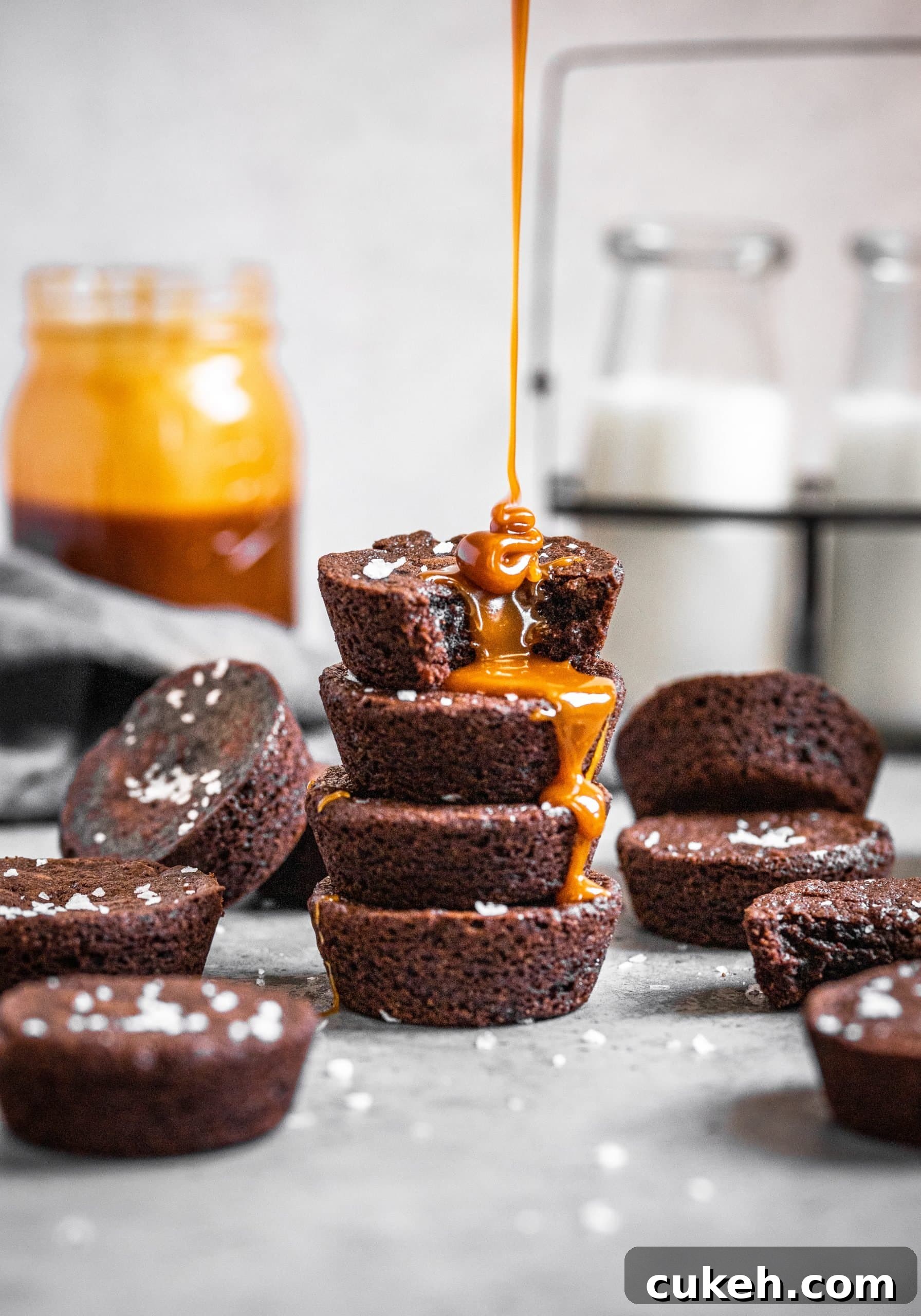 Salted caramel being poured on top of a stack of brownie bites