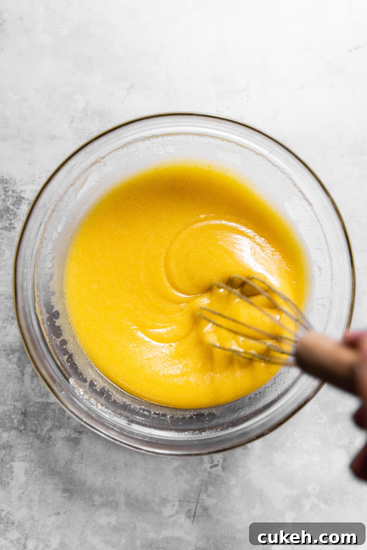 Eggs and vanilla being whisked into wet ingredients.