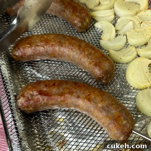 Nicely cooked Italian sausage links cooked in an air fryer with tongs resting on the basket.