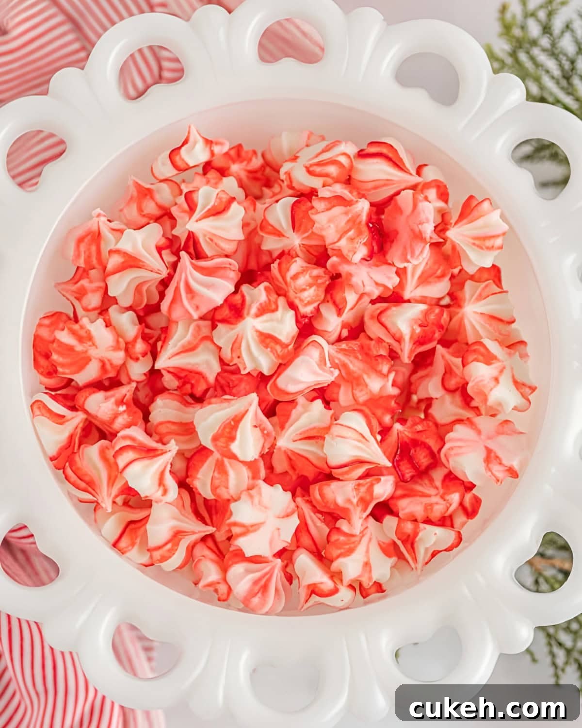 overhead view of red and white christmas cream cheese mints in a milk glass bowl.