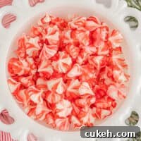 overhead view of red and white christmas cream cheese mints in a milk glass bowl.