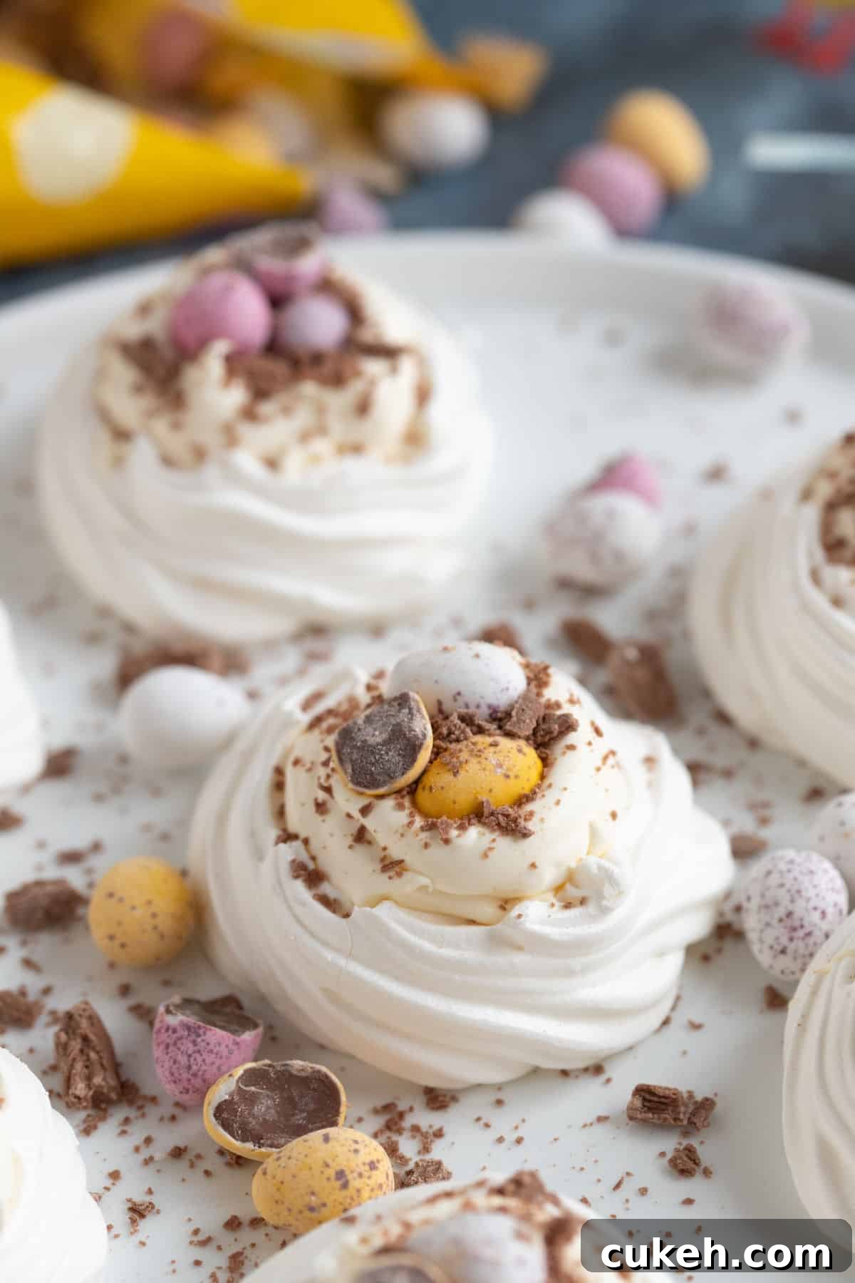 Meringue nests filled with cream and mini eggs on a white plate.