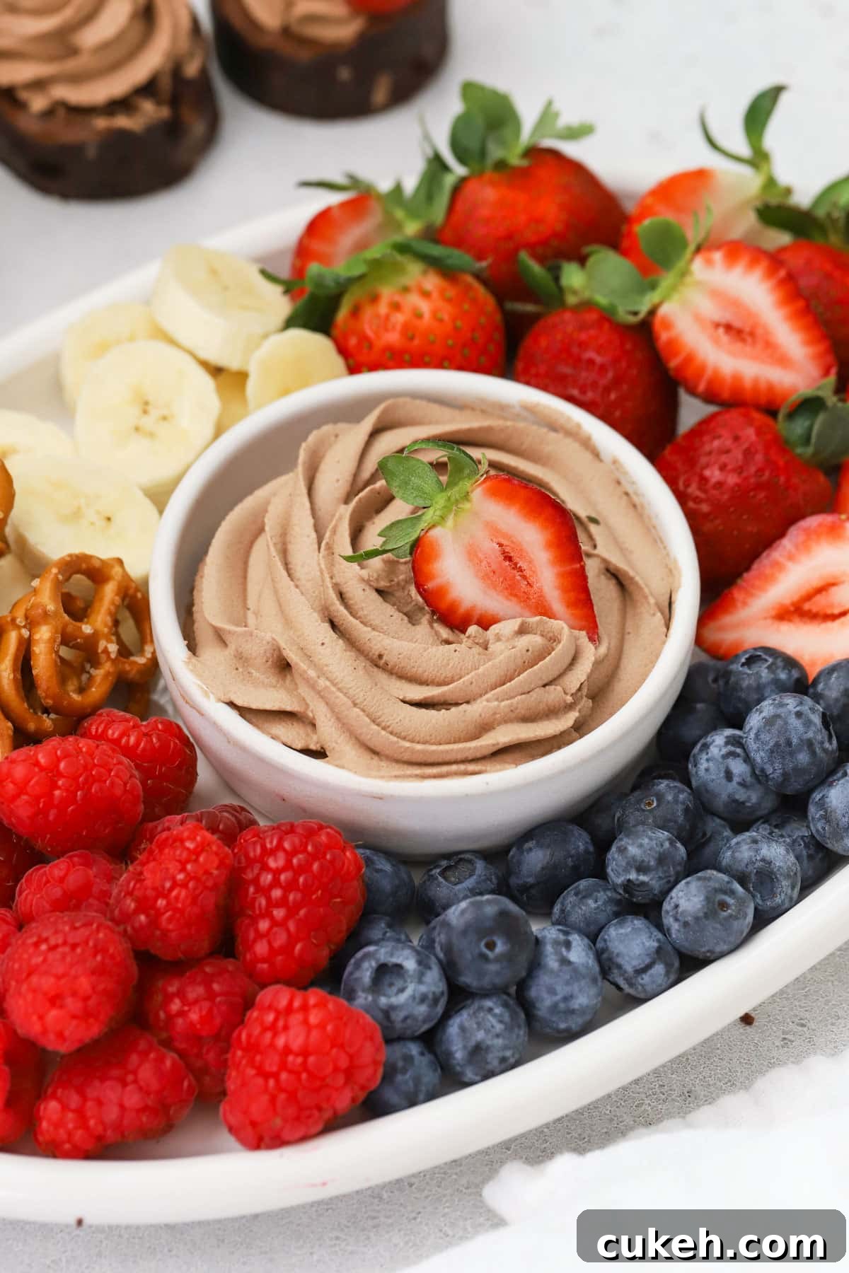 A bowl of chocolate whipped cream surrounded by colorful fresh fruit