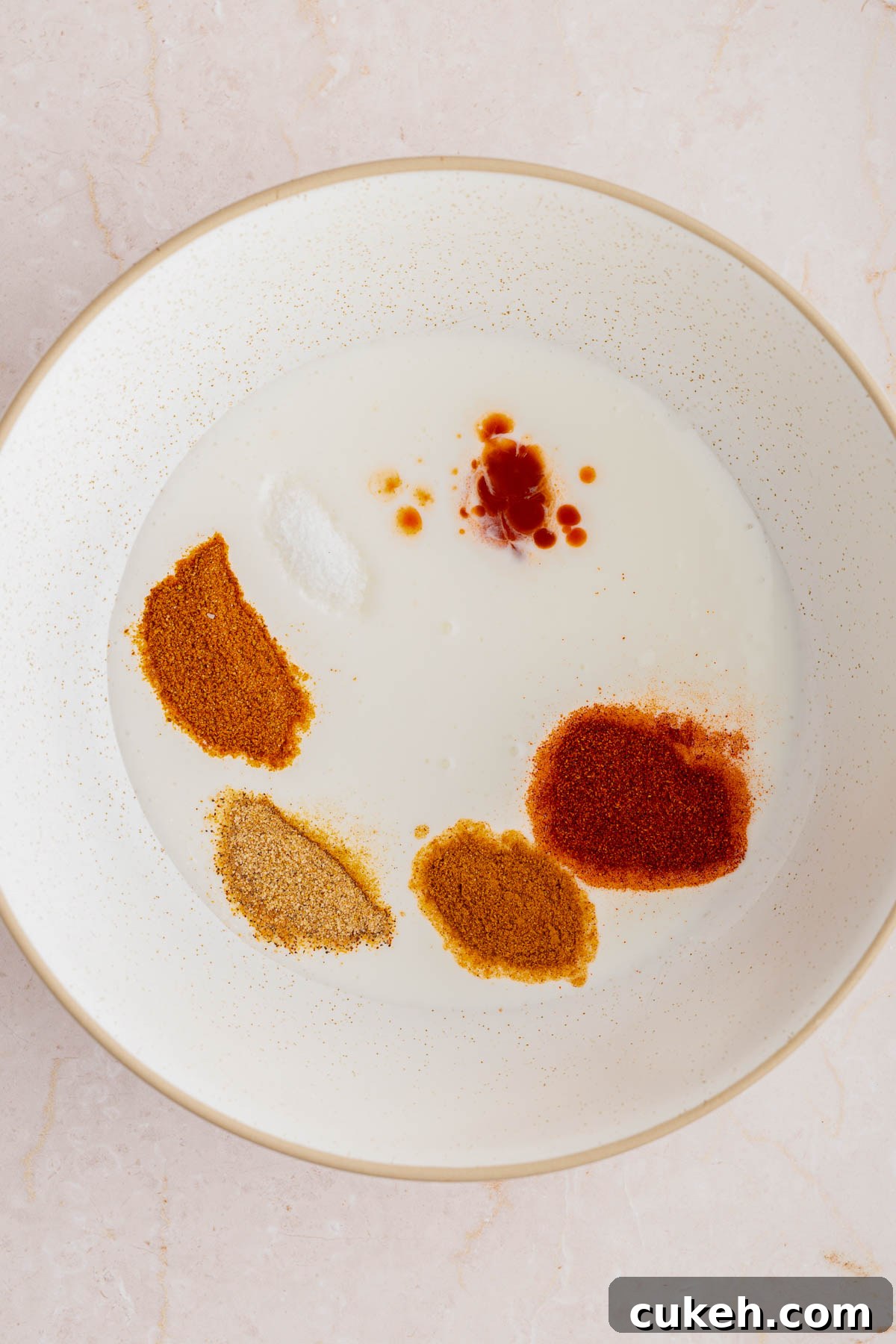 The ingredients for the buttermilk coating in a large white bowl on a countertop.