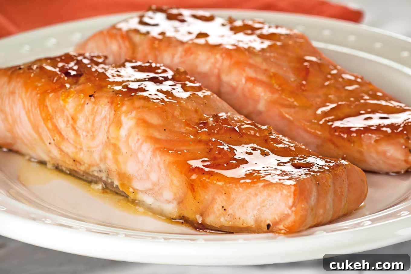 Orange Marmalade Bourbon-Glazed Salmon Recipe for Dinner 3 Close-up of two orange marmalade and bourbon glazed salmon on a white serving plate.