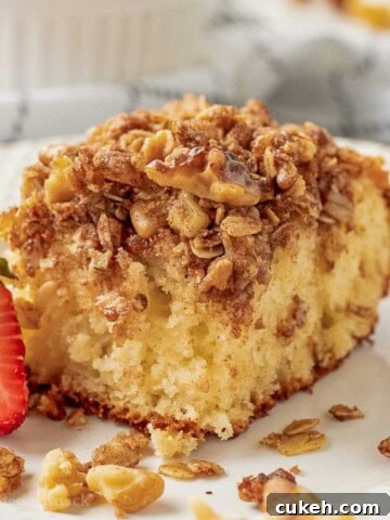 Slice of baked coffee cake with strawberry on plate.