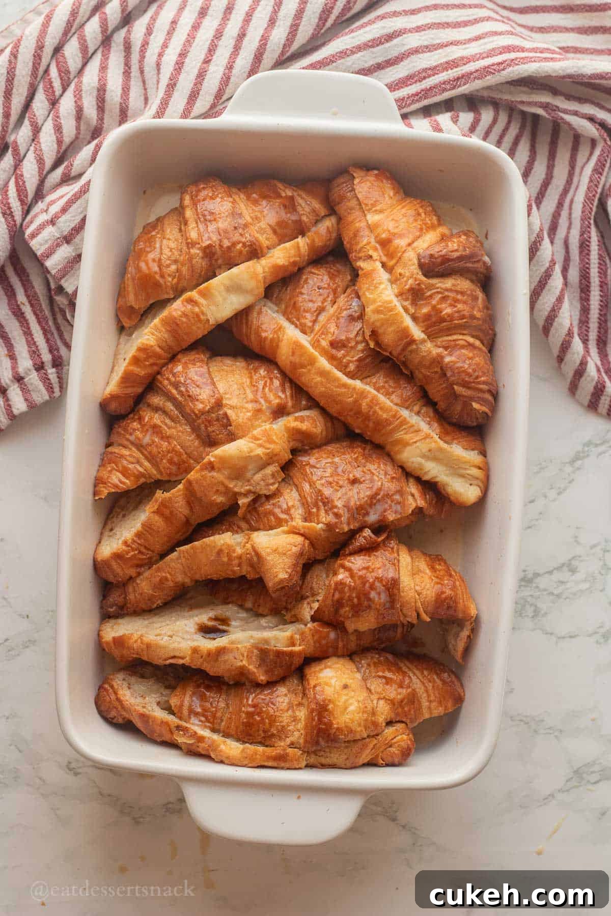 Sliced croissants in custard in pan.