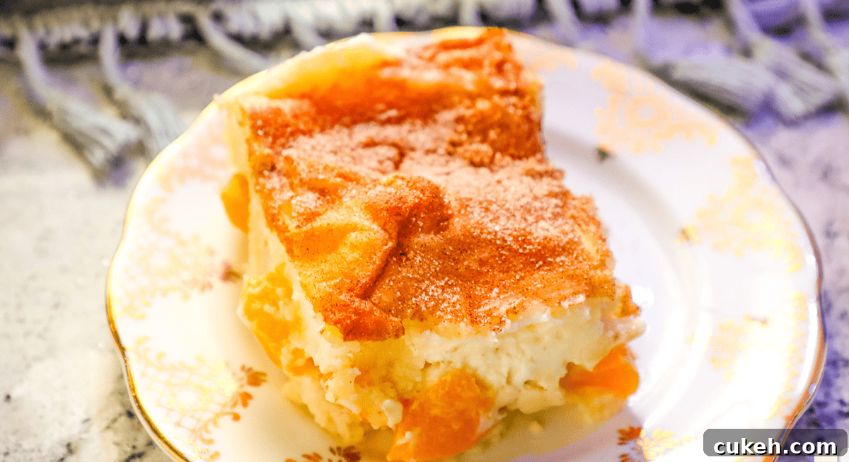 a closeup of peach cake with a cream cheese and cinnamon sugar topping on a white plate.