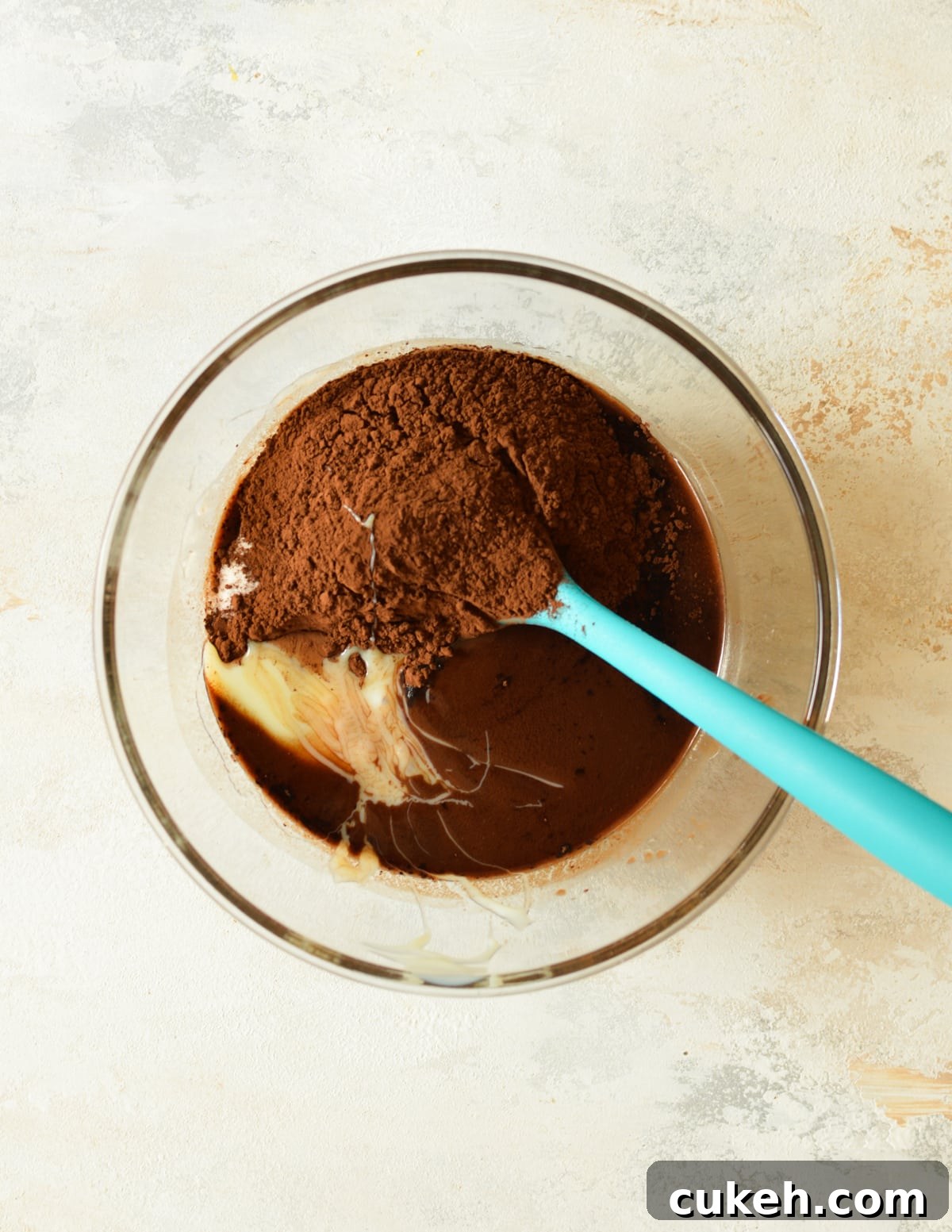 a bowl of melted chocolate with cocoa powder and sweetened condensed milk