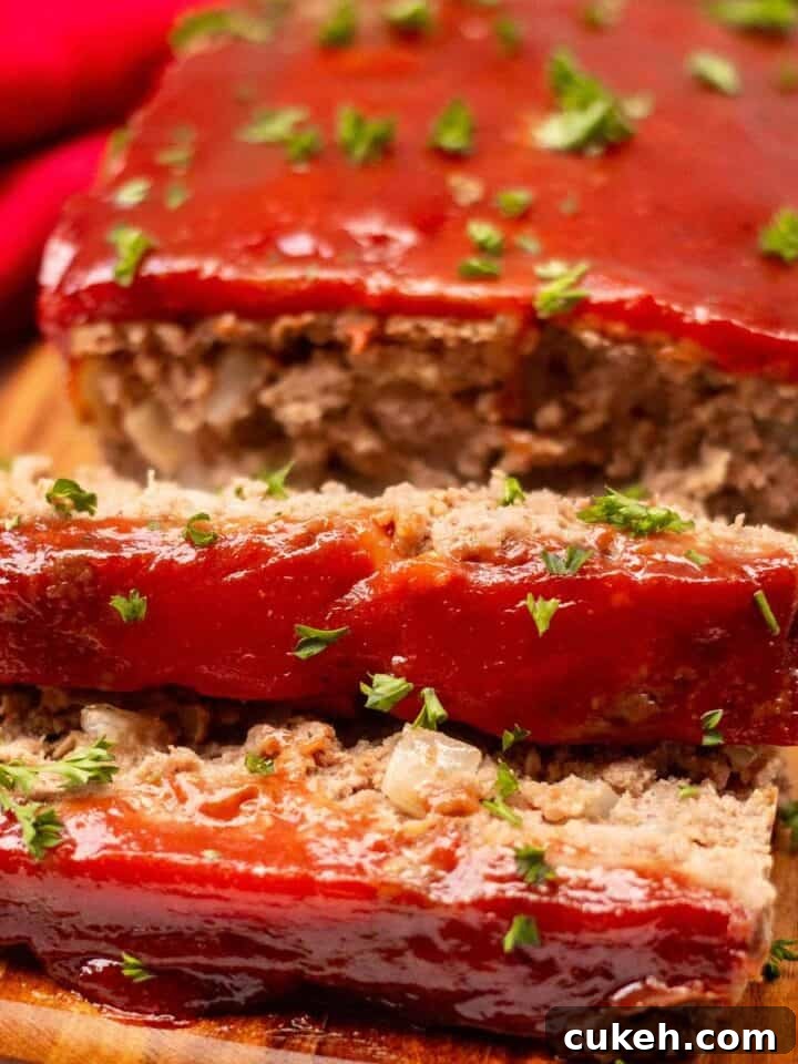 Meatloaf on a cutting board garnished with fresh parsley. Two one-inch slices are cut off the loaf.