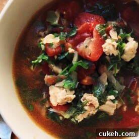 Fragrant Chicken Tomato Soup in bowl near yellow napkin and spoon.