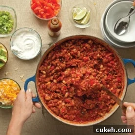 Serving turkey chili from pot next to chili toppings.