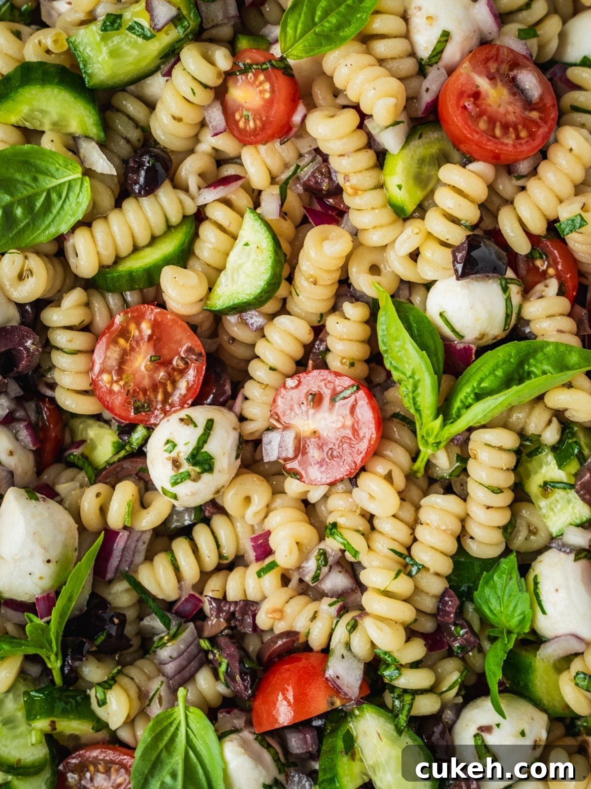 Mediterranean pasta salad with cherry tomatoes, cucumber, mozzarella balls, and olives.