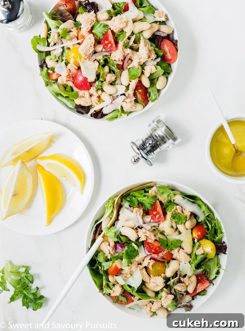 Two bowls of white bean and tuna Salad with lemon and olive oil dressing served on the side.