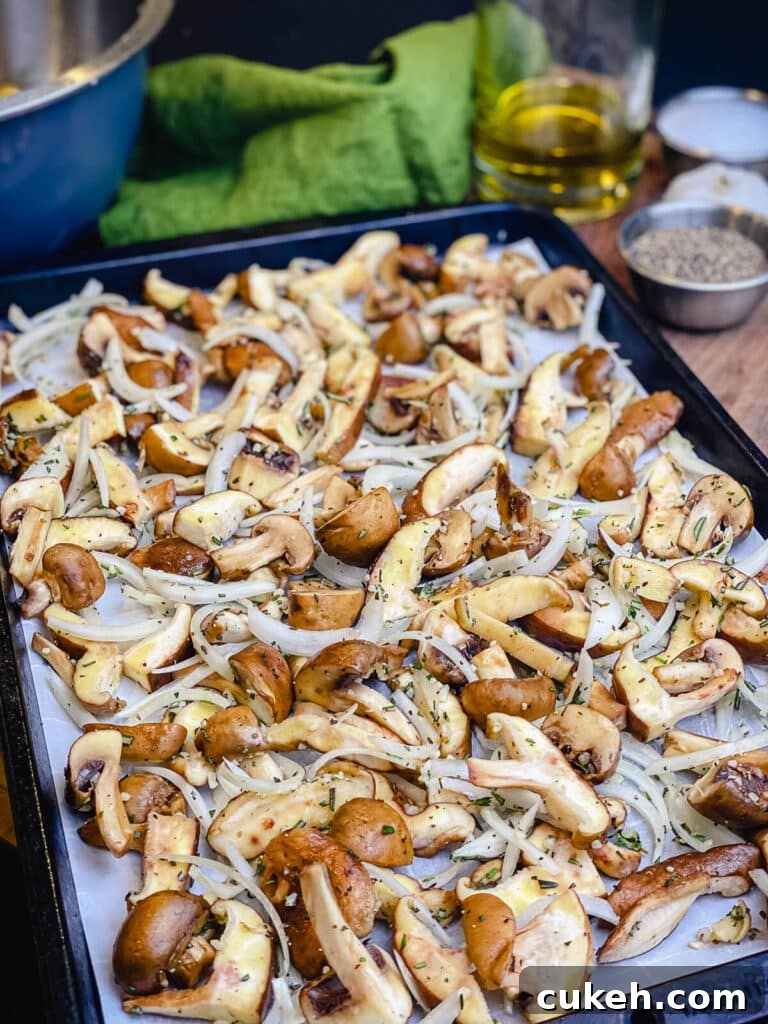 mushrooms and onions on a parchment lined baking sheet