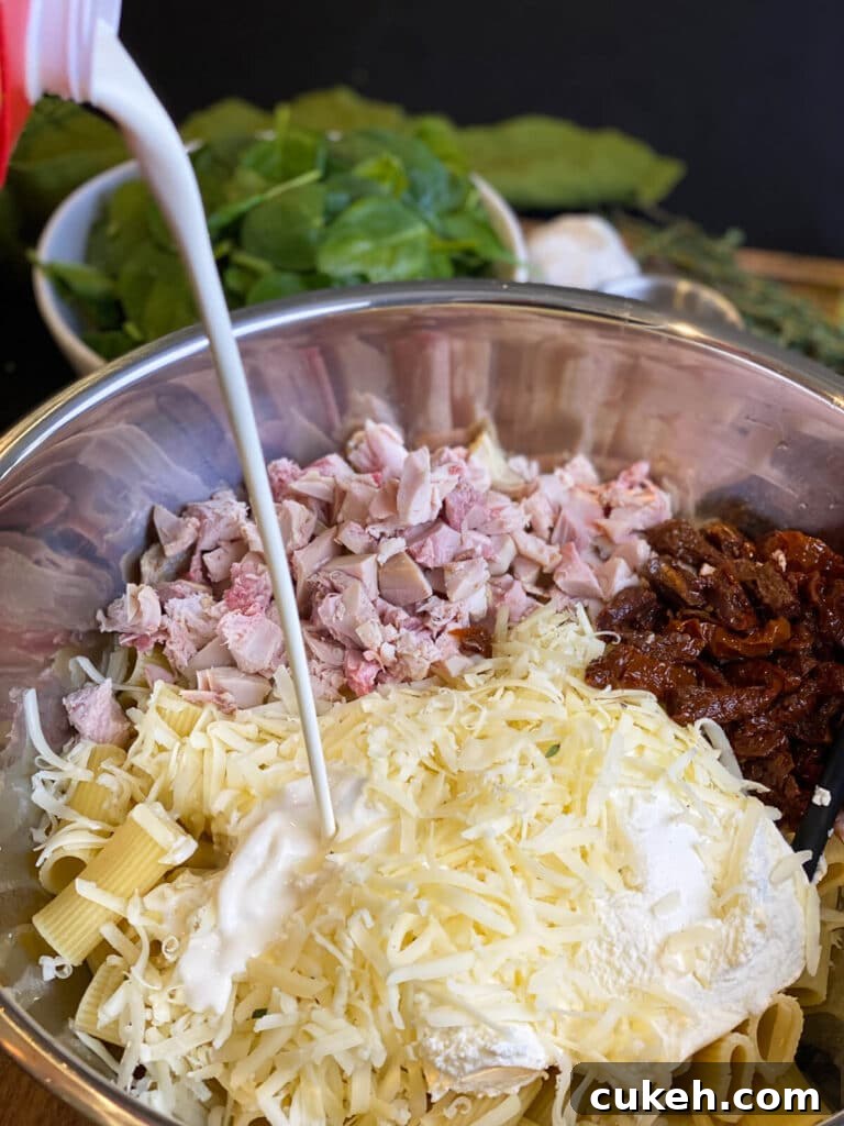 heavy cream being added to the ingredients for a creamy chicken pasta bake