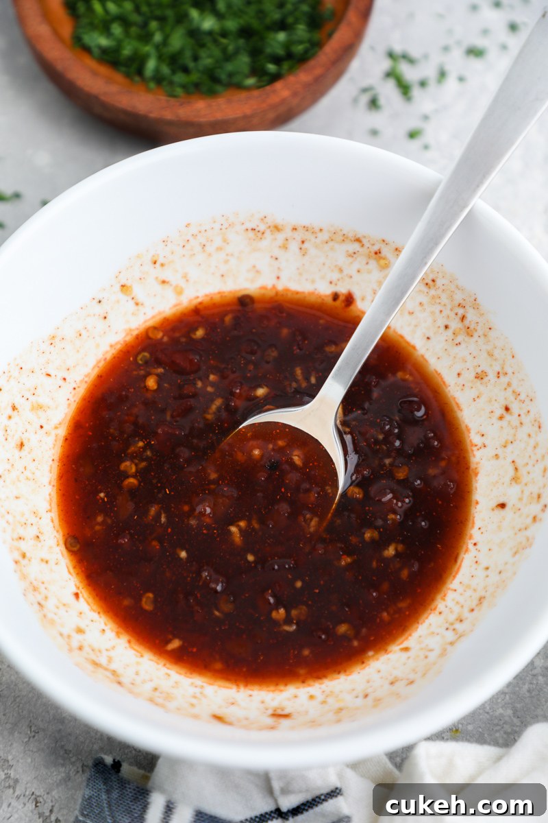 A small white bowl filled with chipotle maple sauce sitting next to a small wooden bowl of chopped parsley