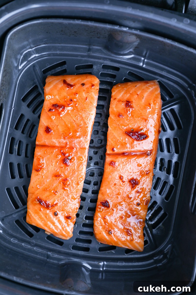 2 salmon fillets brushed with a chipotle maple sauce sitting in an air fryer basket