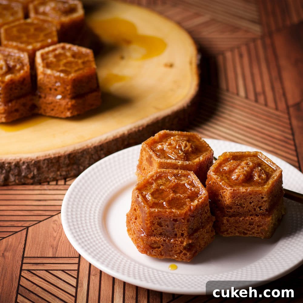 A serving of honey cake with whisky sauce baked in a honeycomb pan on a white plate.