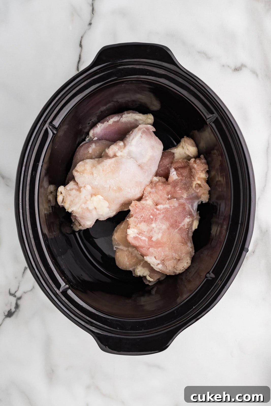 overhead view of chicken thighs in black slow cooker
