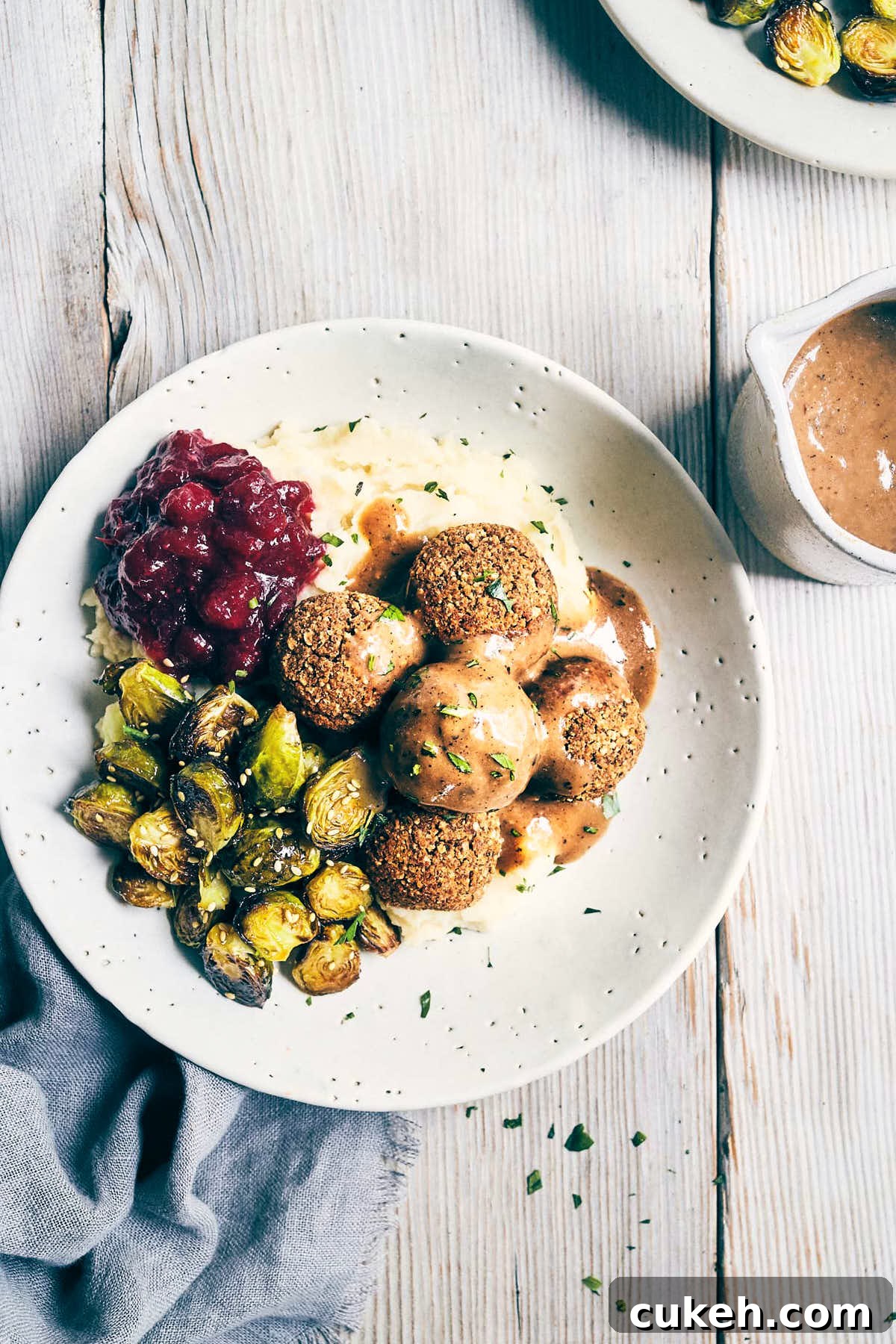 Dish of vegan meatballs, baked brussels sprouts and mashed potatoes topped with mushroom miso gravy