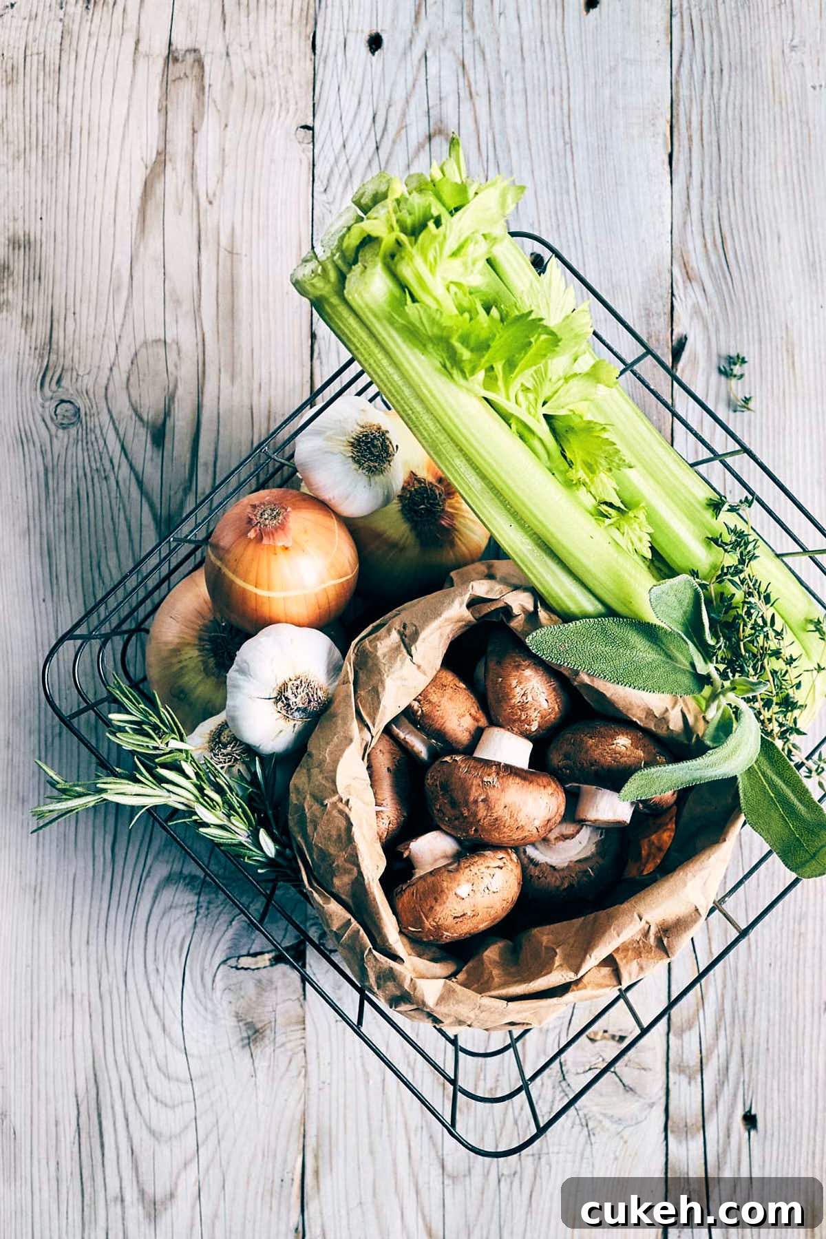 Basket of ingredients like mushrooms, garlic, onions, celery, thyme, sage and rosemary
