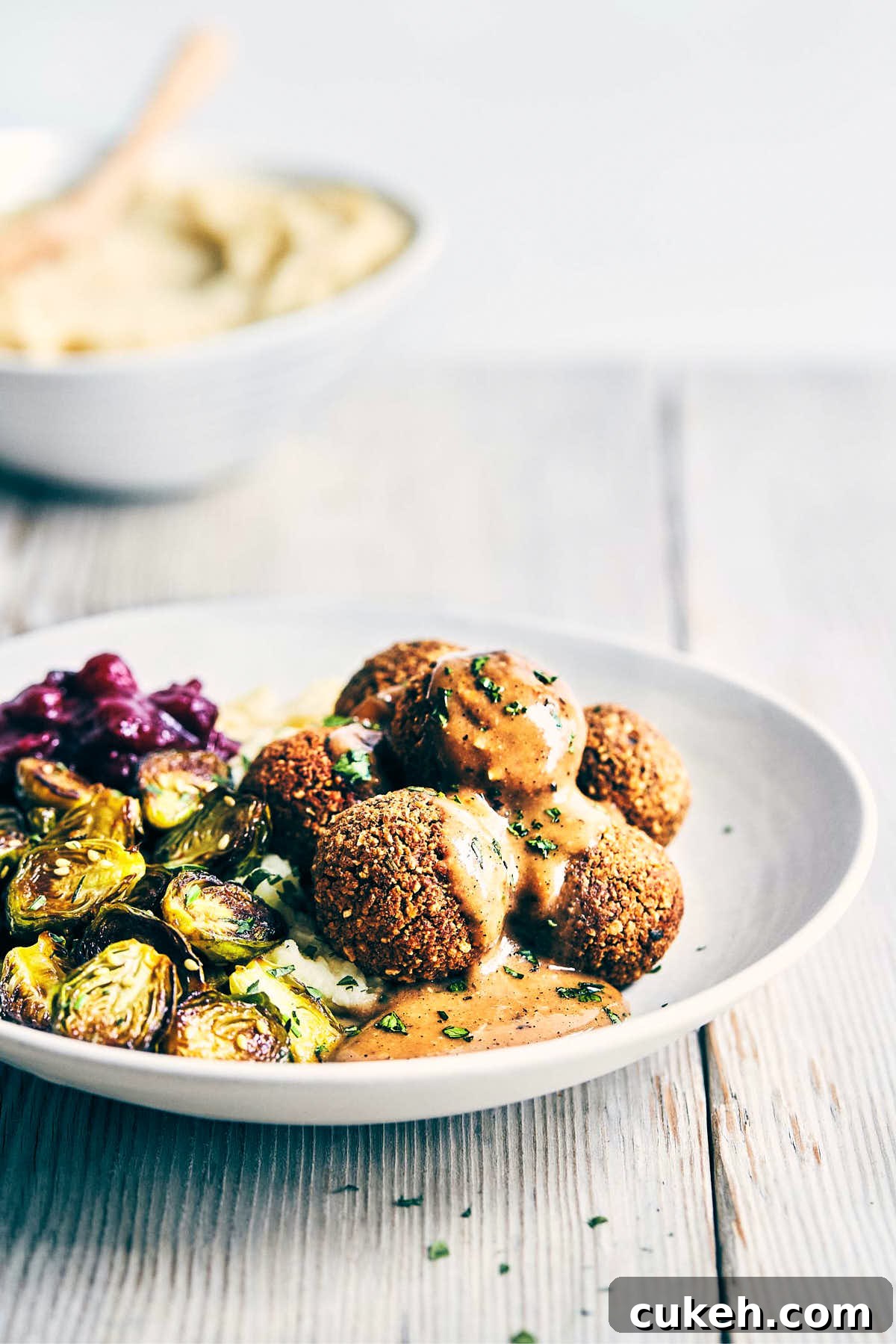 Side view of vegan meatballs with mushroom miso gravy on a wooden surface