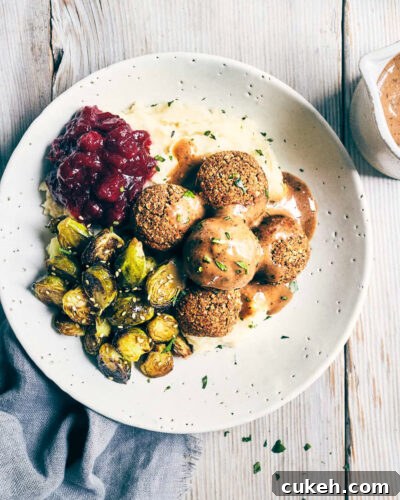 Dish of vegan meatballs, baked brussels sprouts and mashed potatoes topped with mushroom miso gravy